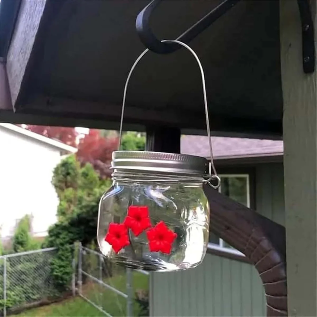 Mason jar hummingbird feeder hanging from an outdoor hook