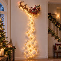 Glowing Santa sleigh wall light beside a decorated Christmas tree
