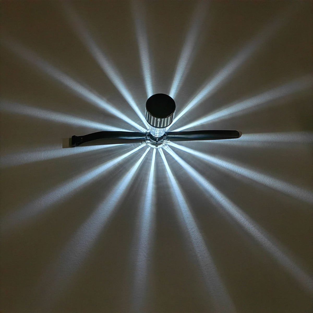 Solar railing light casting a starburst light pattern on a wall
