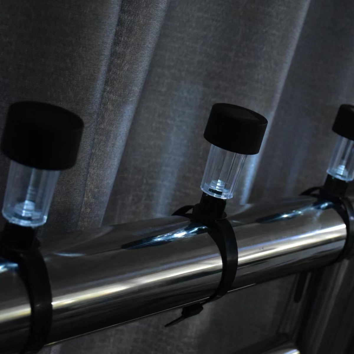 Solar railing lights secured to a metal railing with mounting ties