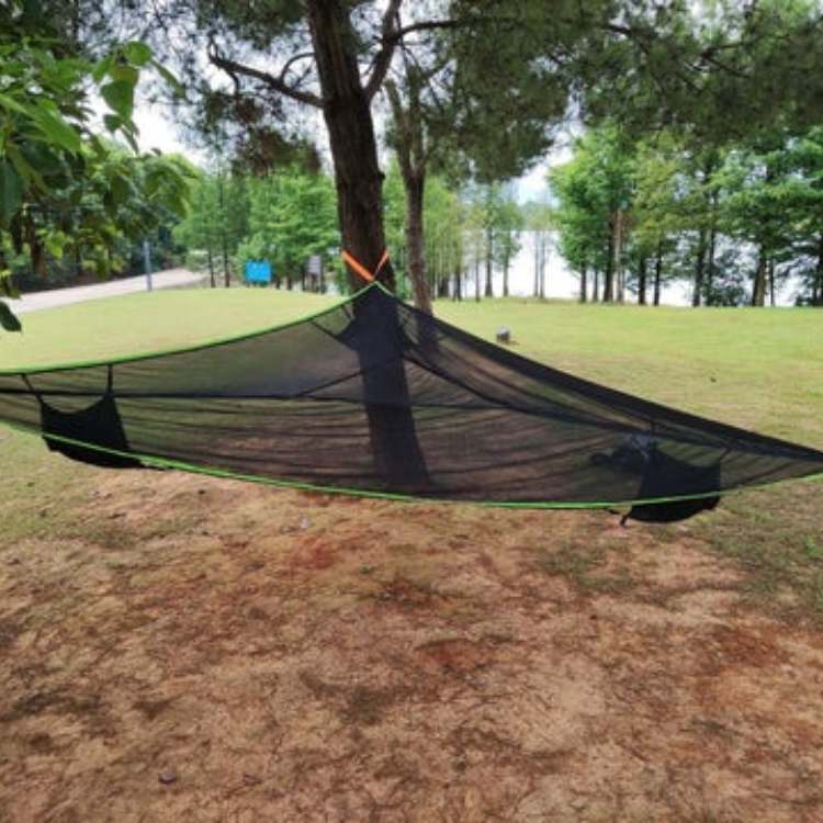 Triangle camping hammock with straps set up outdoors between trees